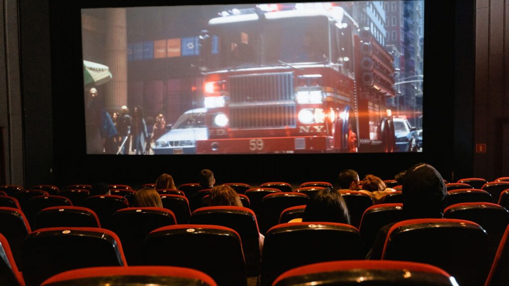 Movie theatre with a movie running and a few cinema-goers in the shot
